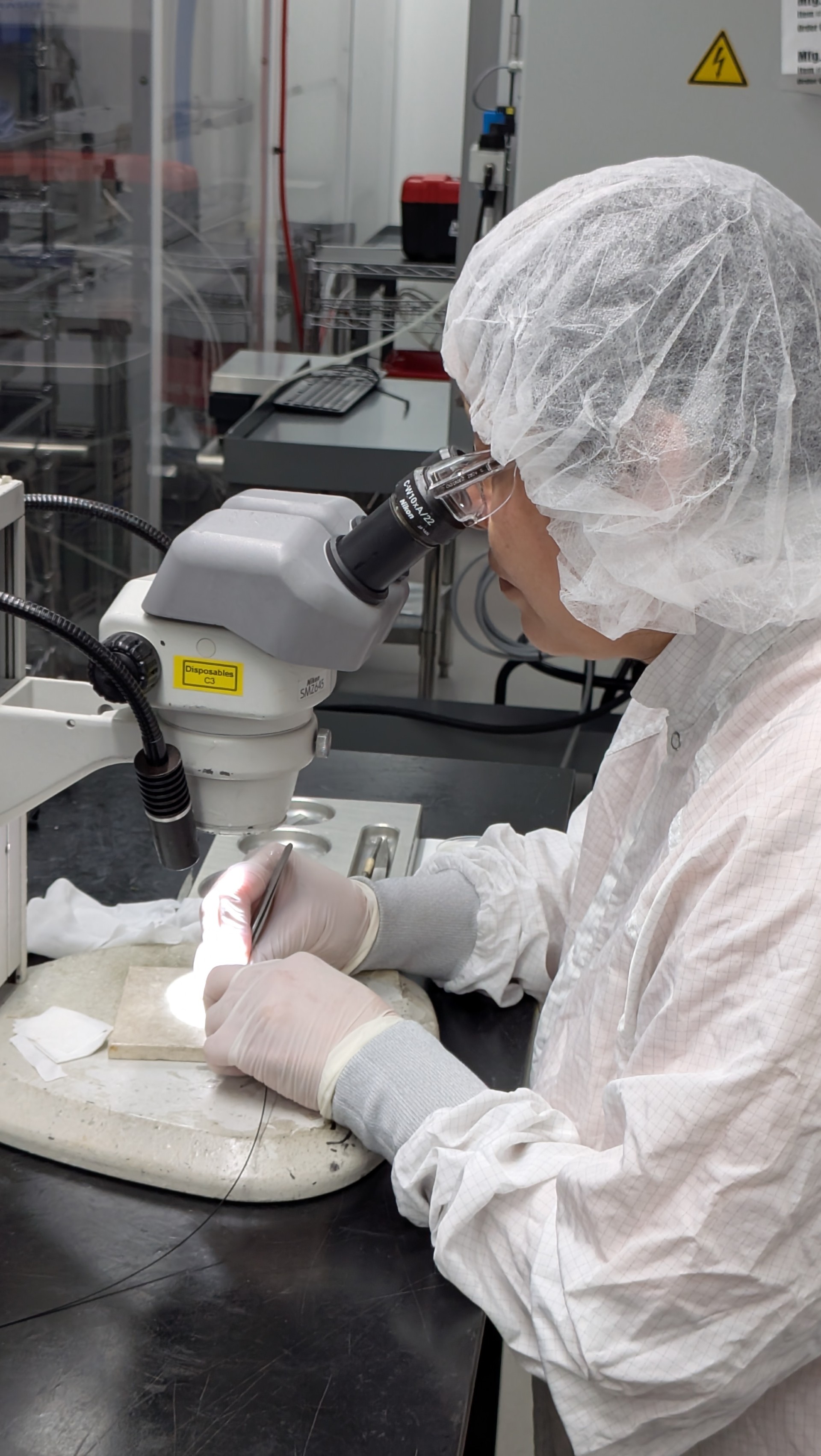 Person in lab looking in microscope
